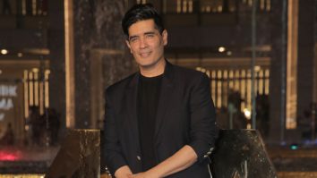 Manish Malhotra poses for paps dressed in a black suit